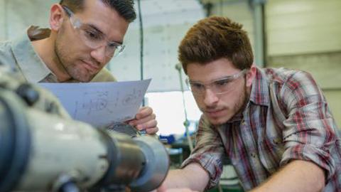 Engineering students setting up machinery from detailed plans in a lab.